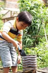 young child digging in a garden pot