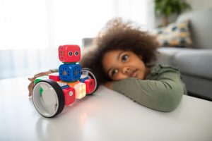 child playing with a robot made out of blocks