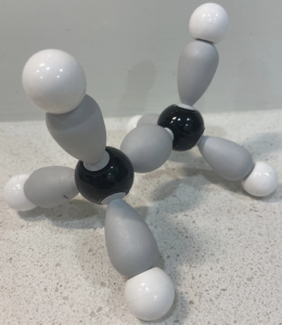 A 3D model of the structure of ethane. A black sphere is bound to another black sphere, and each black sphere is bound to 3 white spheres. The bonds are depicted as teardrop -shaped orbitals. The white spheres bound to each carbon atom point to corners of a tetrahedron.