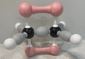 A 3D model of ethene. A black sphere is bound to another black sphere, and each black sphere is bound to 2 white spheres. The grey bonds are depicted as teardrop -shaped orbitals. The white spheres bound to each carbon atom point to corners of an equilateral triangle. Each carbon atom also has an unhybridized p orbital shown with the top half in pink and the bottom half in purple. These p orbitals on adjacent carbon atoms overlap.