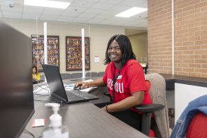 Person sitting at desk with laptop smiling.