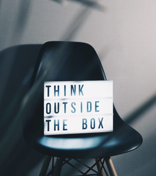 sign with words "think outside the box" on a black chair