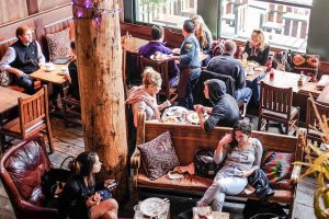 Several groups of people sitting in a coffee shop conversing