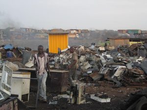 A few people in Ghana working outdoors amongst piles of refuse.