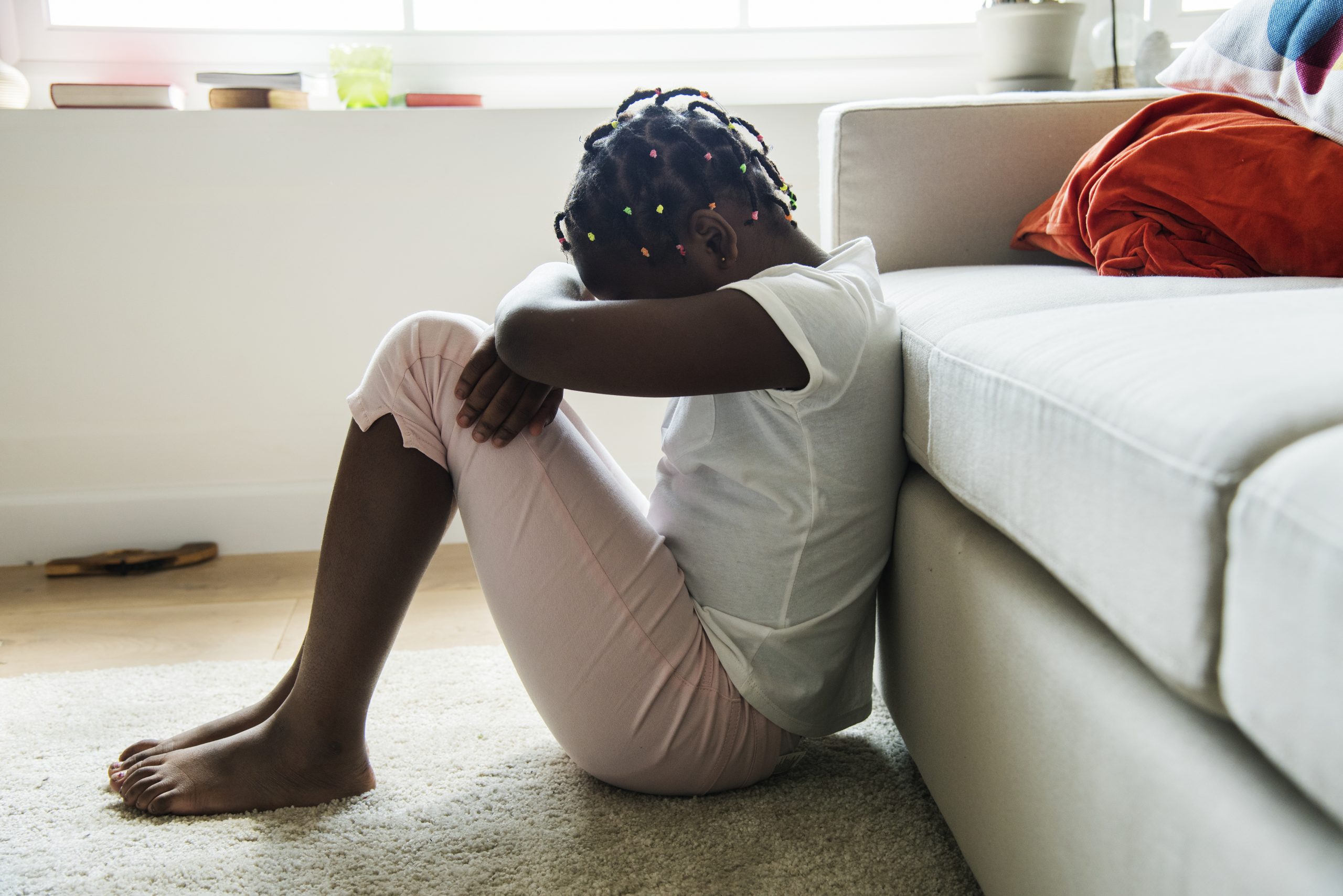 sad girl sitting on floor next to couch