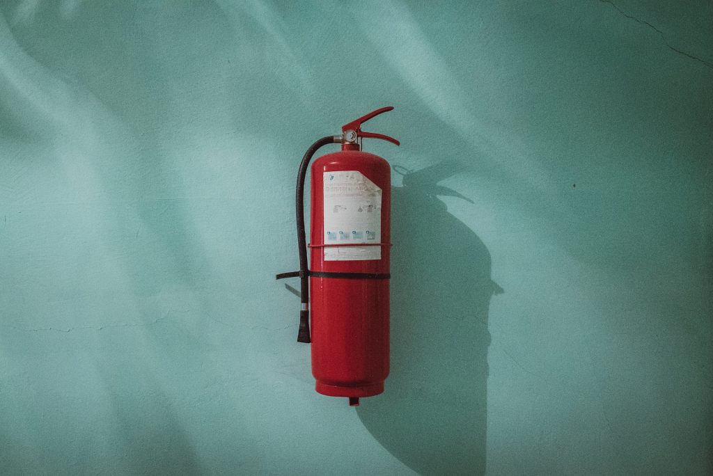 Red fire extinguisher on green wall.