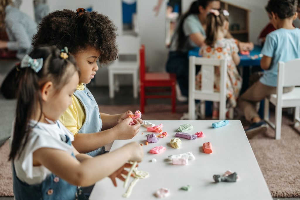 Two girls sitting at a table and sculpting from plasticine.