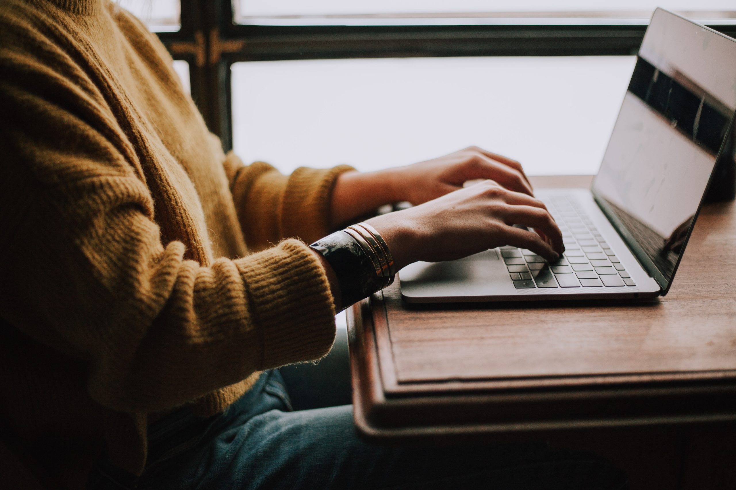 person sitting front of laptop and typing