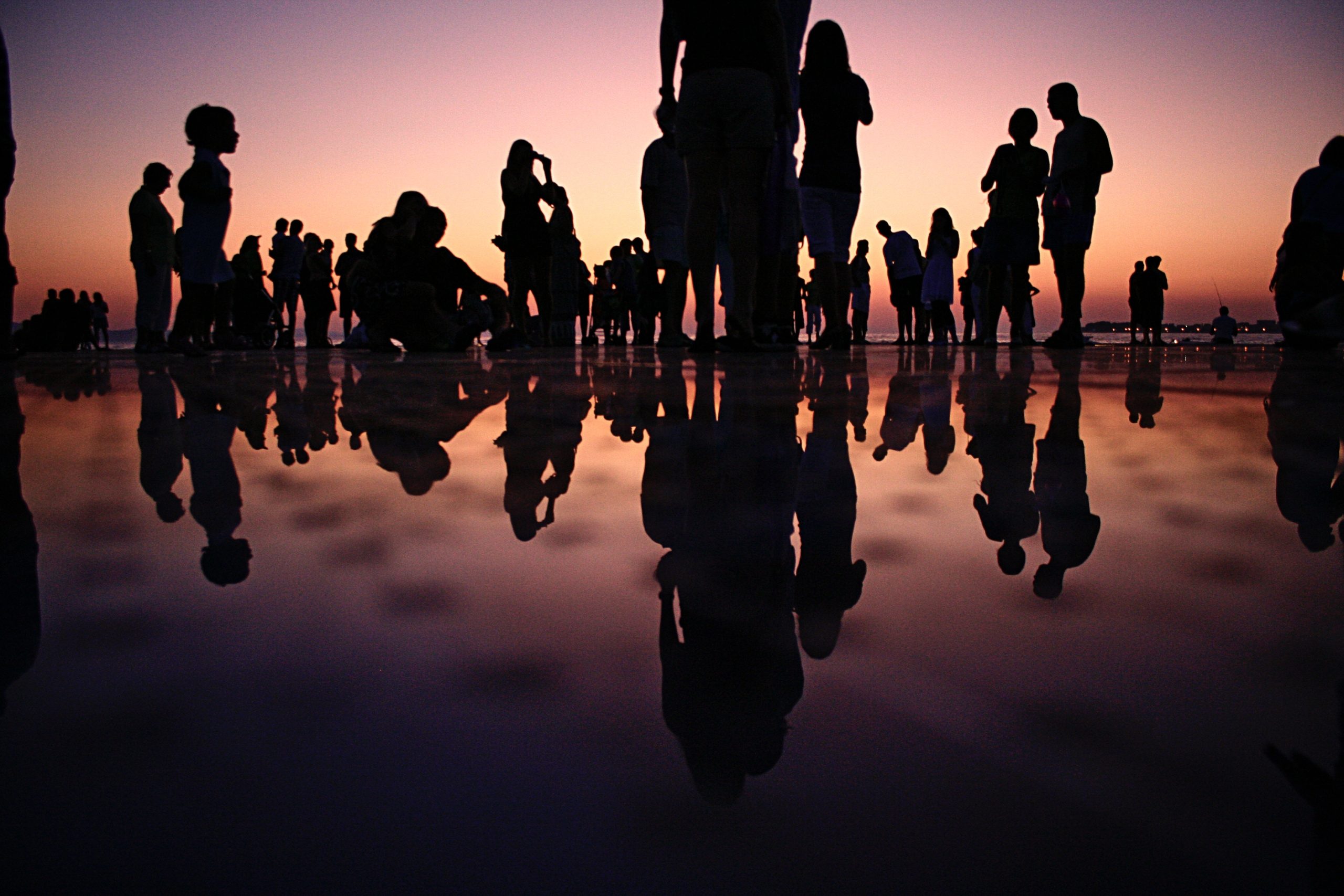 Silhouette of people standing on mirror during golden hour.