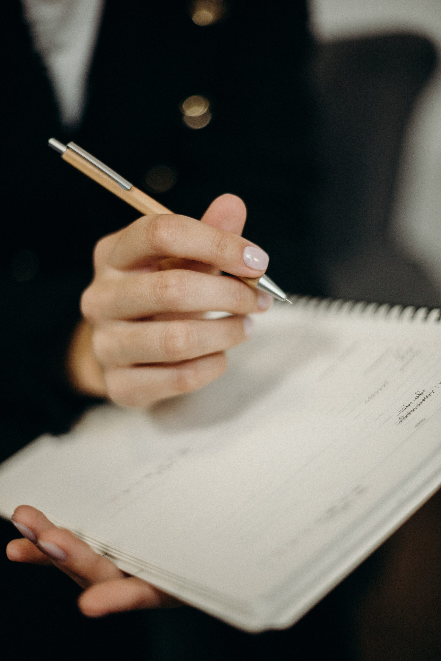 Person Holding Orange Click Pen Writing on Notebook