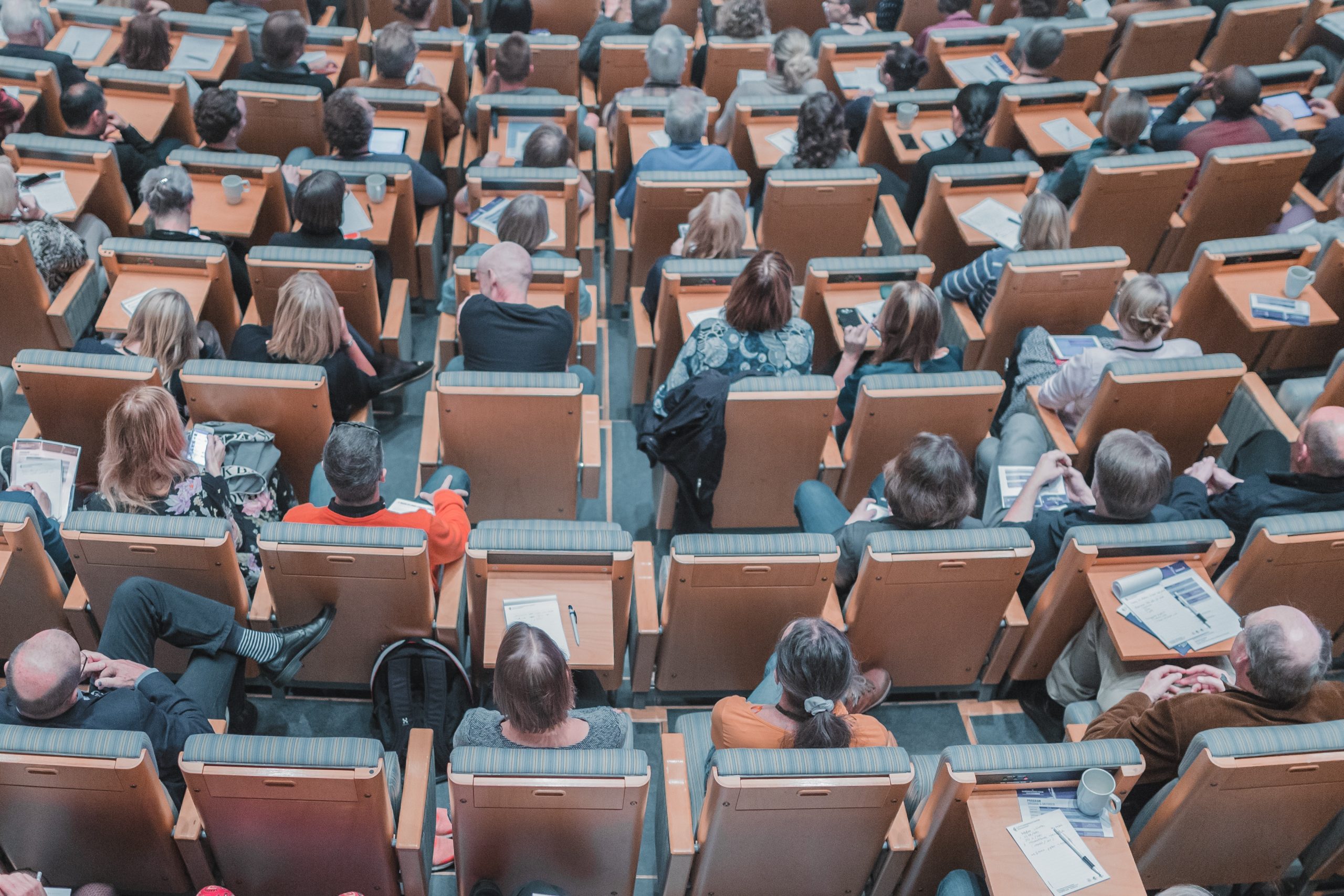 High-angle photography of group of people sitting in a lecture hall.