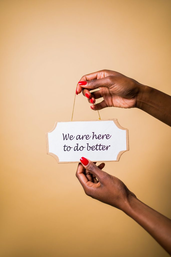 A person holding a sign saying "We are here to do better "