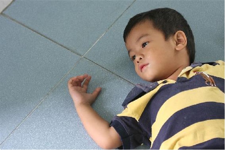 Young child laying down with arm extended.