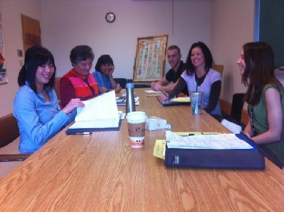 A group of people are sat around a table in what looks like a work meeting.