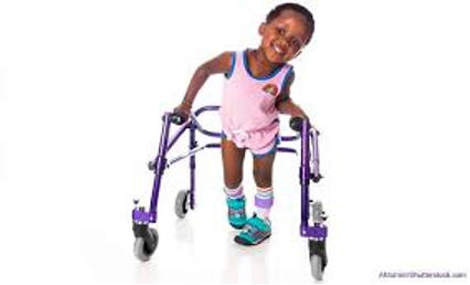 A little girl with cerebral palsy smiling and walking with the assistance of a walker.