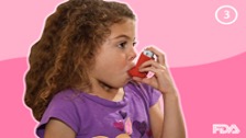 A young girl using a red puffer.