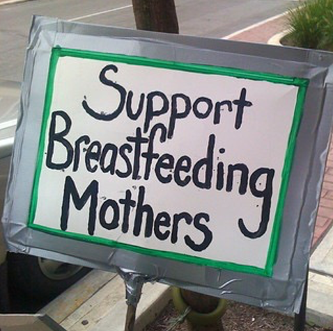 A sign on a sidewalk that says "Support Breastfeeding Mothers".