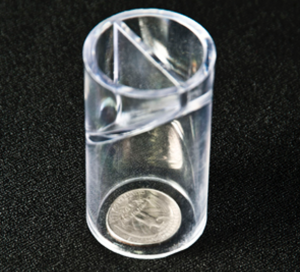 A small glass jar turned upside so it is covering a small coin.