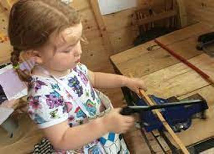 A young girl uses a toy saw.