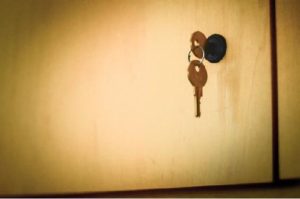 An upper cabinet is closed with a key in it's keyhole.