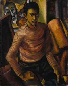 A painting of a sitting African-American man. The man sits in a cluttered space, the unnatural geometry of the furnishings creates a frame around the figure. Behind the figure is a painting of two stylized faces. The man has dark hair and a moustache and wears a striped turtle neck sweater and dark trousers. Both of his hands rest on his legs, as he leans slightly forward.