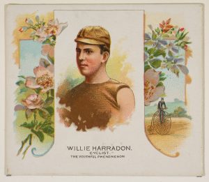 An illustrated image of a young white man wearing a brown cap and a brown top with no sleeves. Floral decorations take up the left and right of the figure, which is visually enclosed and separated from these decorations by a white rectangle. Just below the decorations on the right side, there is a small figure riding a penny-farthing-style bicycle. Just below the central figure, text reads. "Willie Harradon. Cyclist. The Youthful Phenomenon".