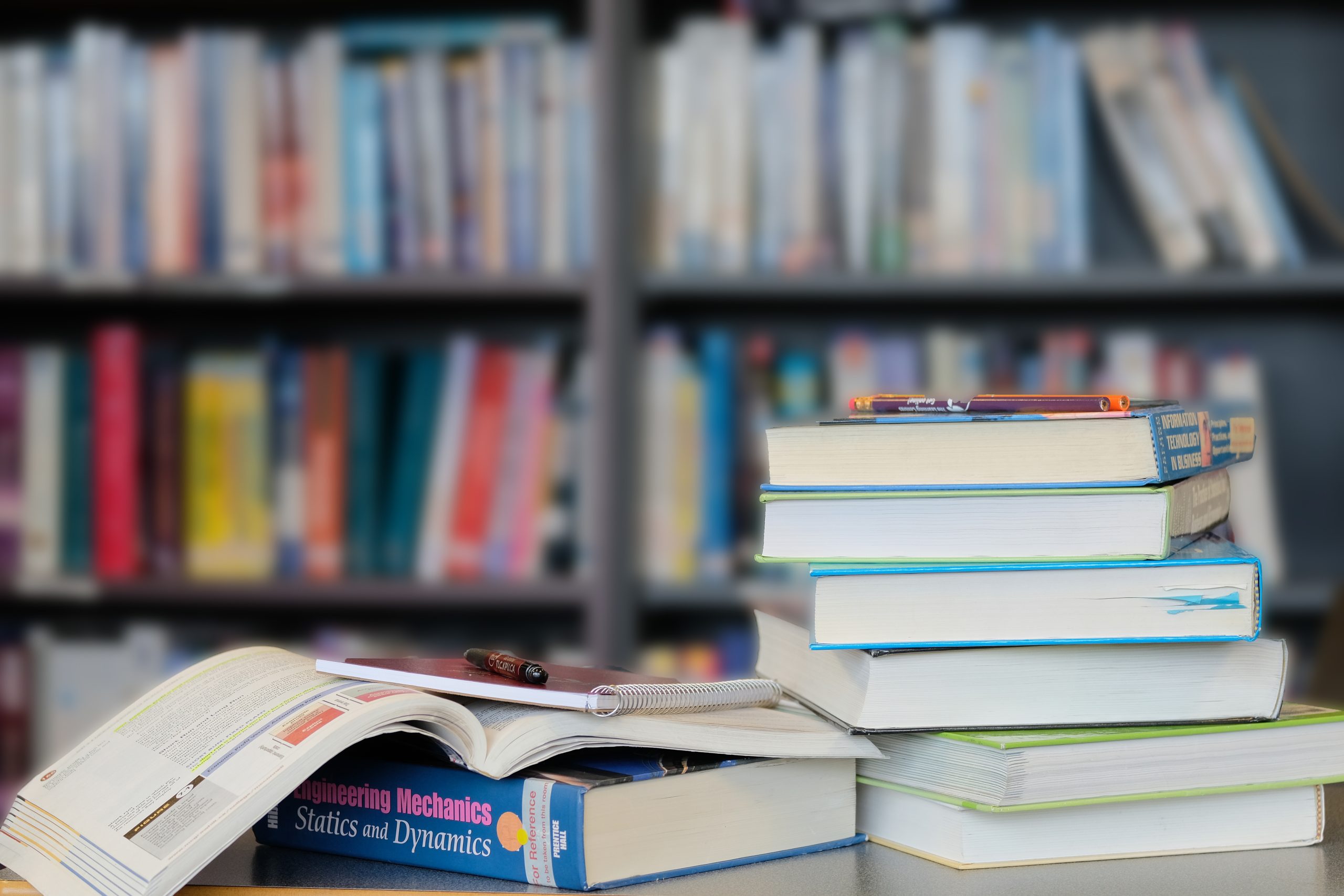 Photo of a stack of textbooks in front of a bookcase