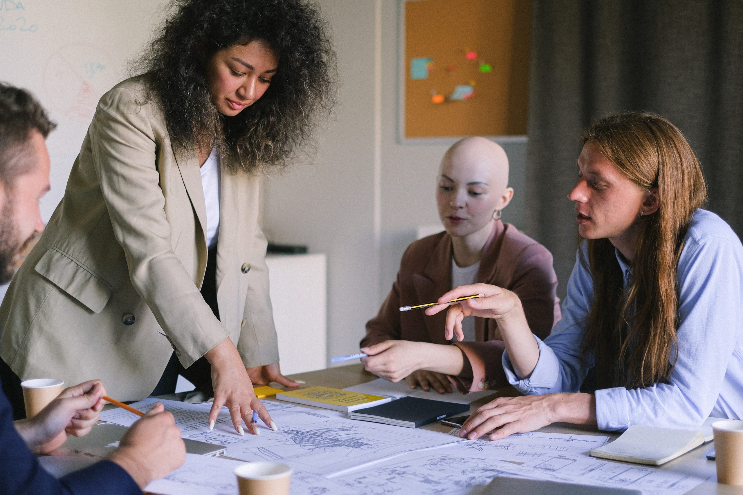 A group of colleagues brainstorming in boardroom while reviewing diagrams