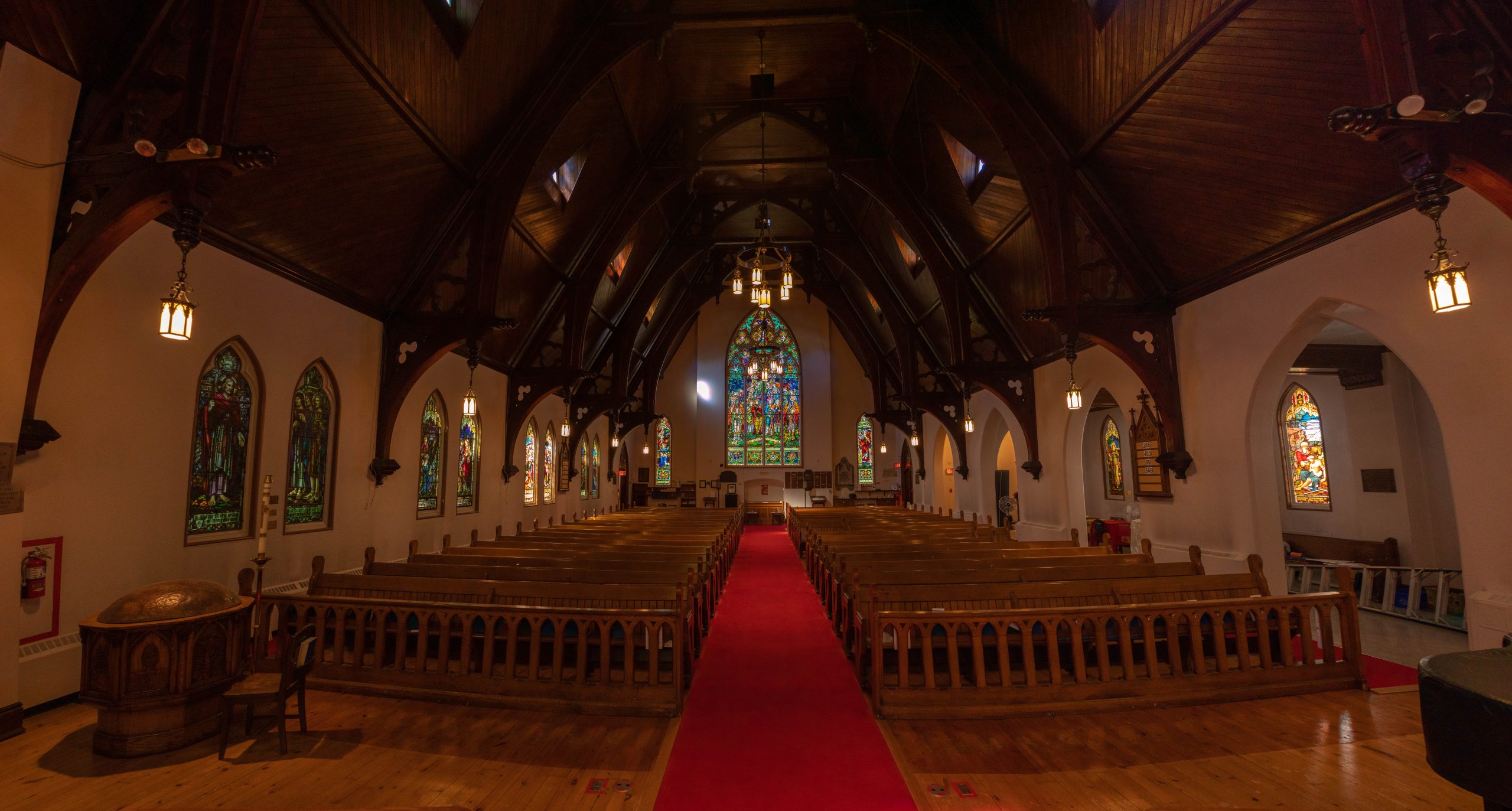 View of church nave. Rows of pews and stained glass windows