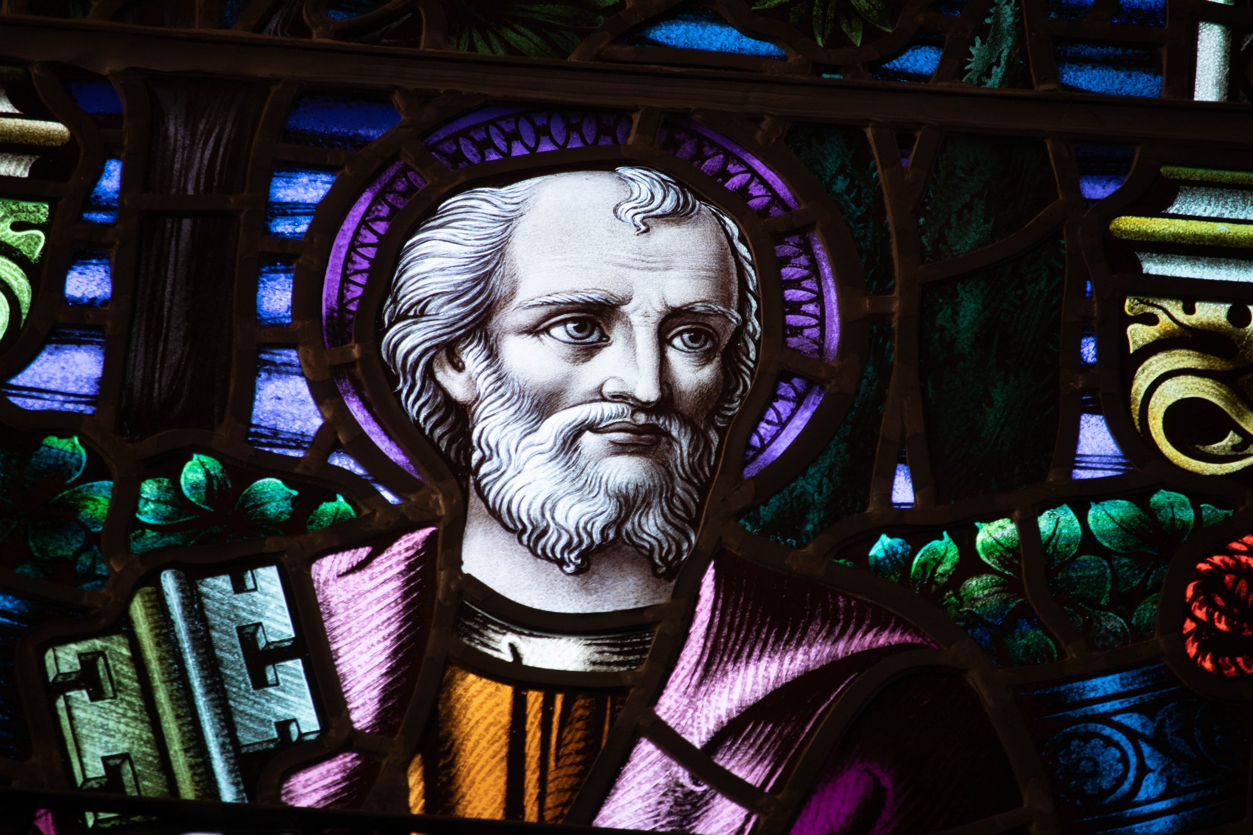 Detail of stained glass window. Bearded man holding oversize key.