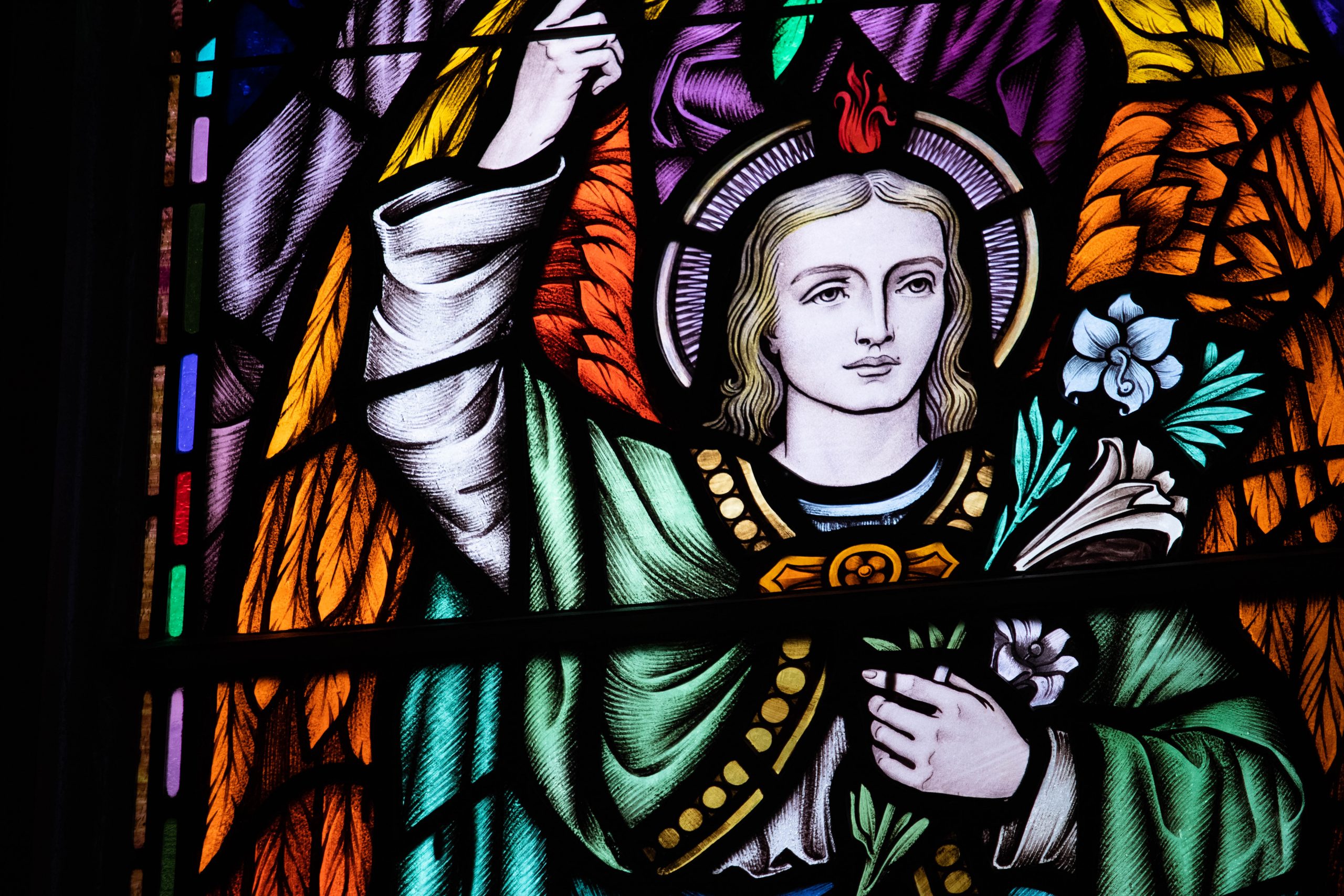 Detail of stained glass window showing male holding flowers.