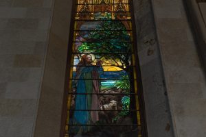 Stained glass window showing a man and lamb.