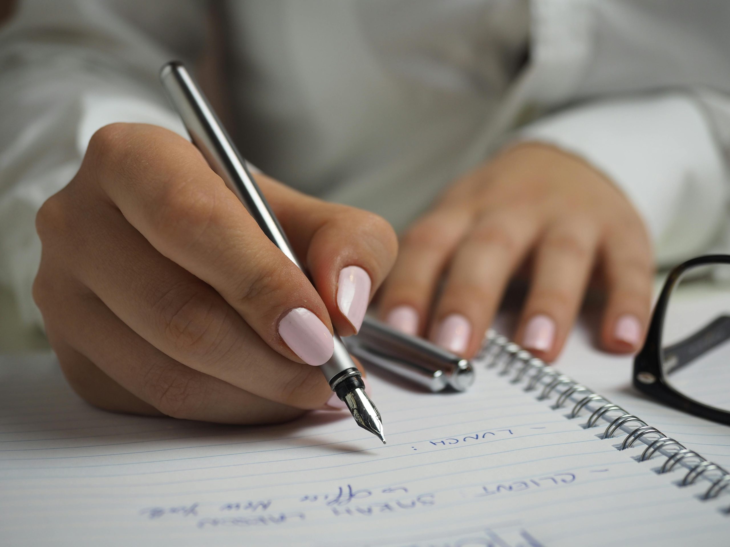 Close up of person's hands holding and pen and writing in a notebook