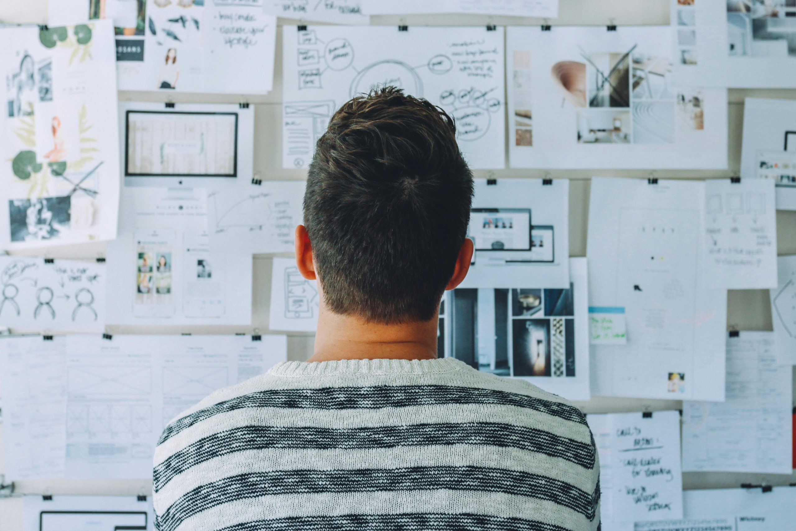 Back of a man's head facing a white board with writing and drawings