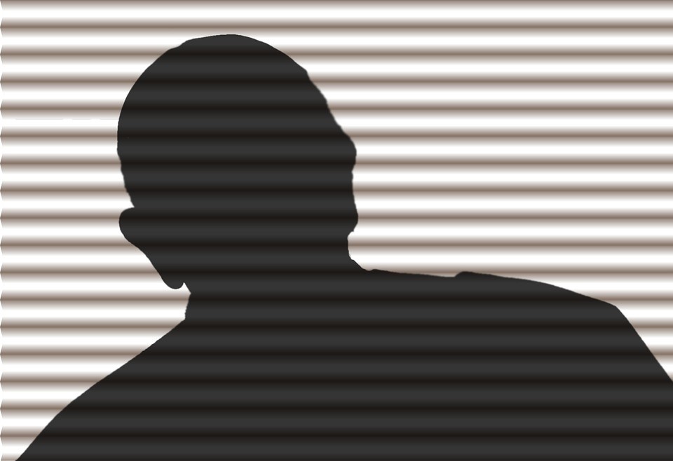 a person in silhouette behind blinds