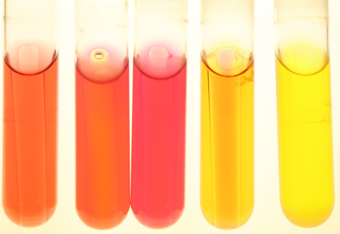 Shows five test tubes, each containing a different coloured solution