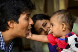 Baby touching a man's cheek while being held by a woman