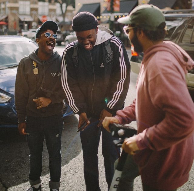 3 men standing on a street in a city and laughing