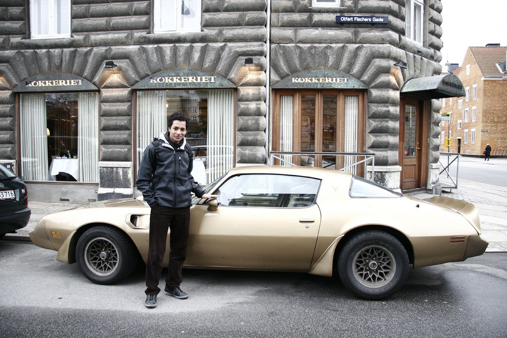 Young man standing next to a luxery car