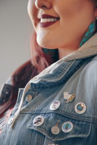 Smiling Indigenous woman displaying pins on jacket