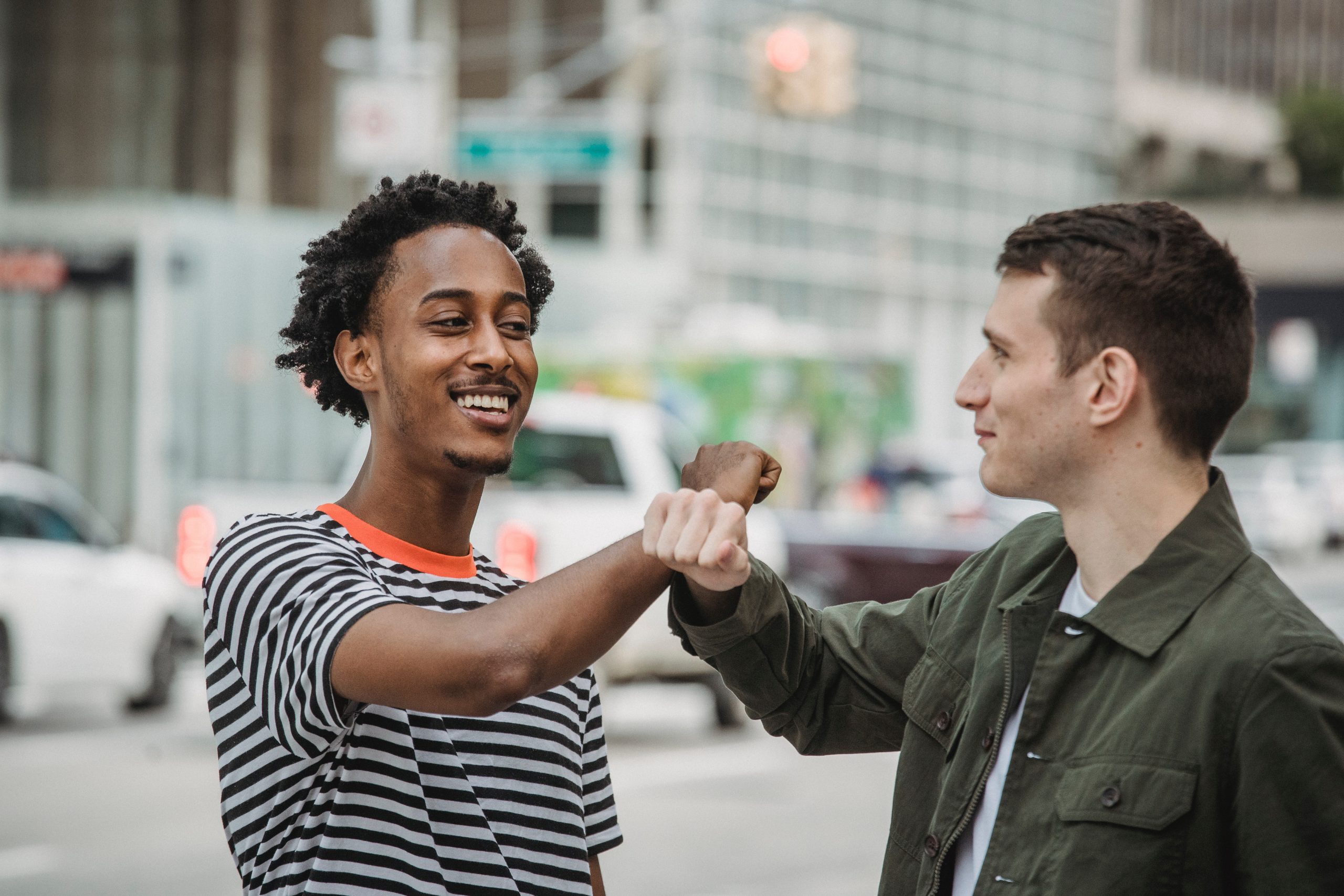 Happy multiethnic men bumping arms on street