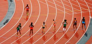 Runners lined up in lanes on a track, prepping for a race.