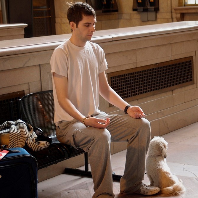 man seated in public place meditatitng