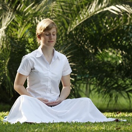woman sitting outdoors in a meditative state smiling