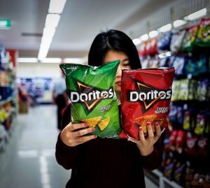 photo of a female comparing the back of two bags of doritos