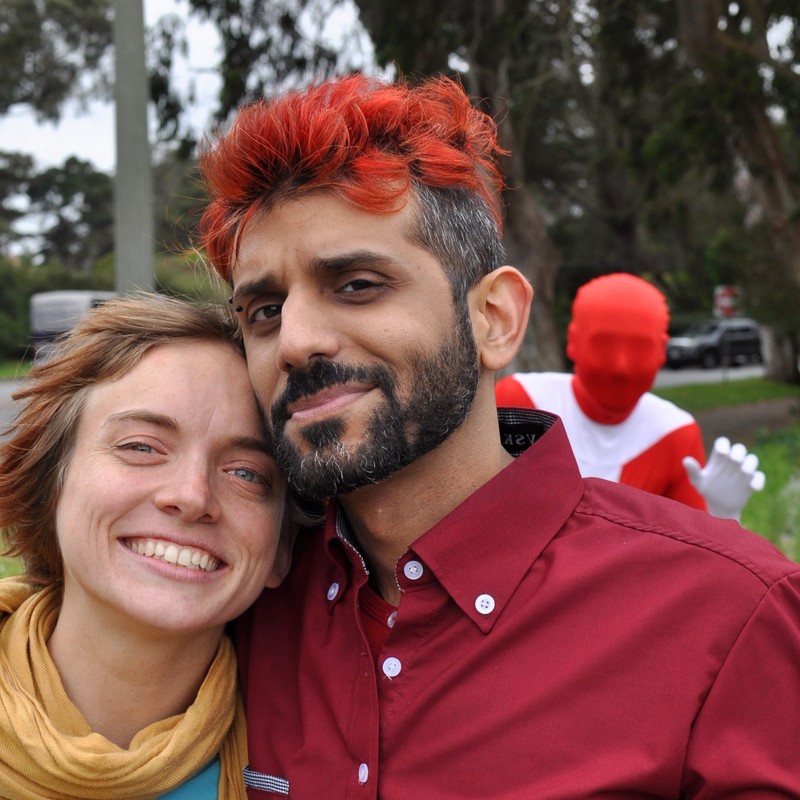 man and woman posing for camera with a person in the background wearing a morph suit