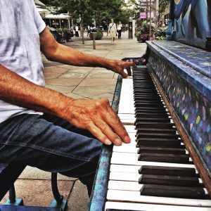 photo of mans arms playing piano outside