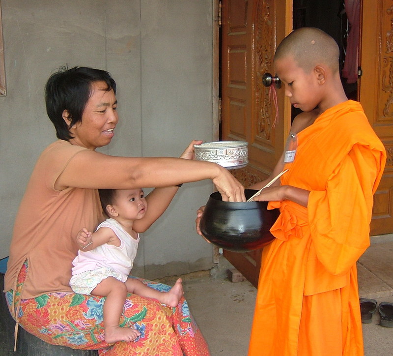 young monk sharving food with woman and baby