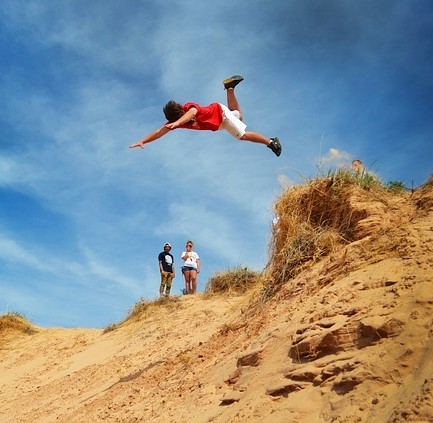 Photo of a child jumping into a sand dune