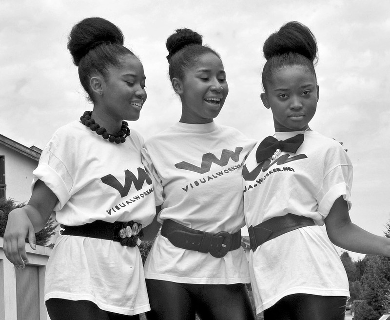 black and white photo of three girls wearing the same outfit wmiling